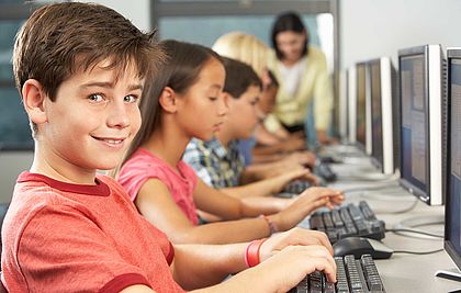 Kinder in einer Reihe vor PC-Bildschirmen