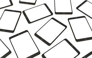 Viele Tablets liegen ungeordnet auf einem Tisch.