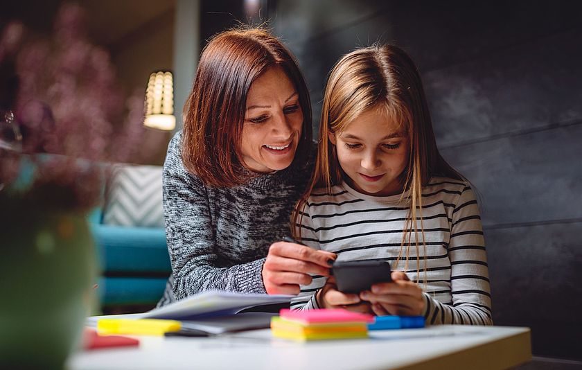 Mutter und Tochter schauen gemeinsam auf ein Smartphone
