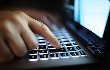 Hände auf beleuchteter Laptop-Tastatur
