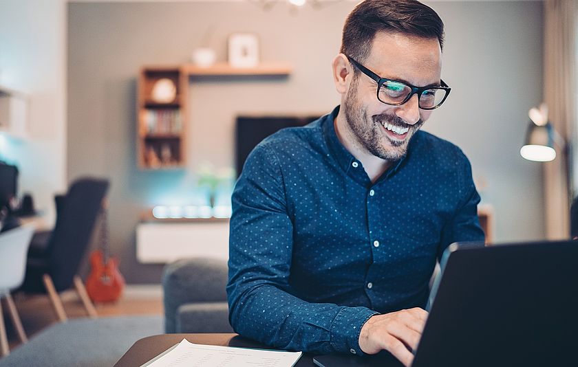 Junger Mann arbeitet von zu Hause an seinem Laptop im Homeoffice.
