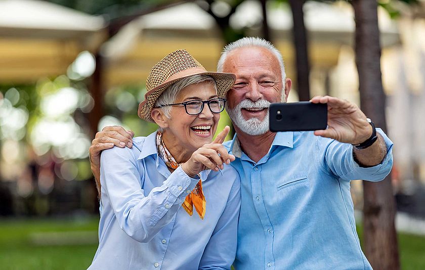 Älteres Paar schaut gemeinsam auf ein Smartphone.