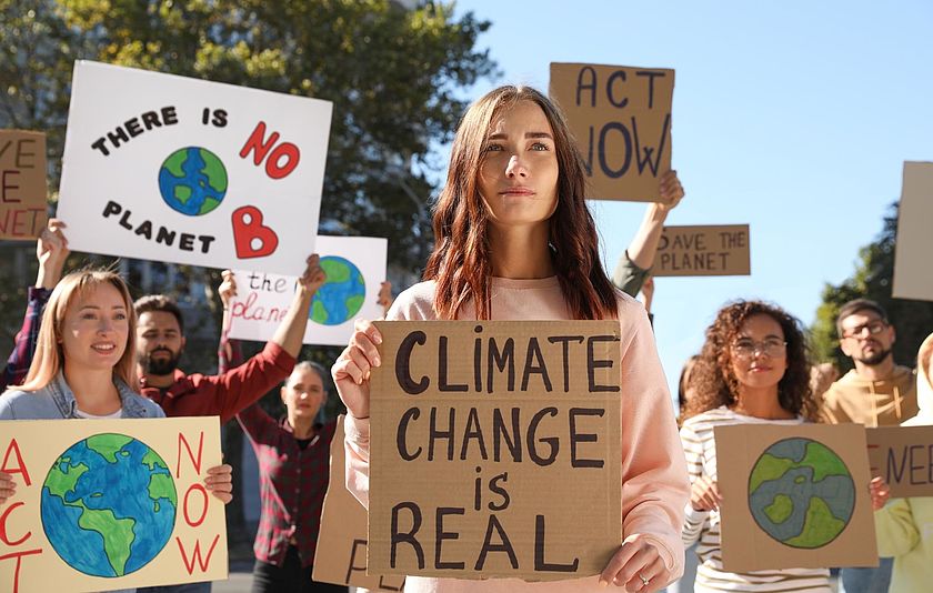 Junge Erwachsene bei einer Klima-Demonstration Eine Gruppe junger Erwachsener auf einer Klima-Demo. Sie halten Schilder hoch, auf denen auf denen übersetzt steht "Der Klimawandel ist real" und "Es gibt keinen Planeten B".
