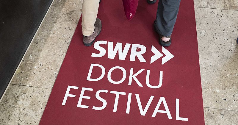 Hinweis auf rotem Teppich auf das SWR Doku Festival