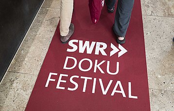 Hinweis auf rotem Teppich auf das SWR Doku Festival