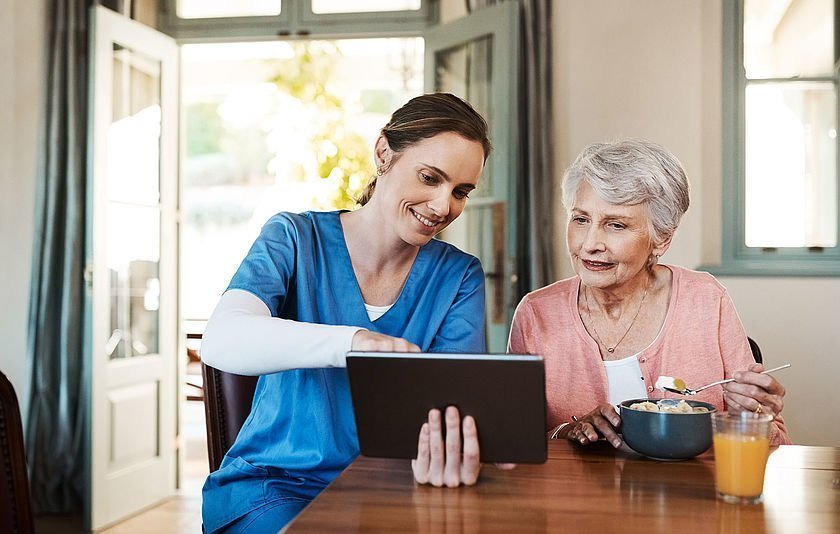 Krankenschwester mit Seniorin vor Tablet