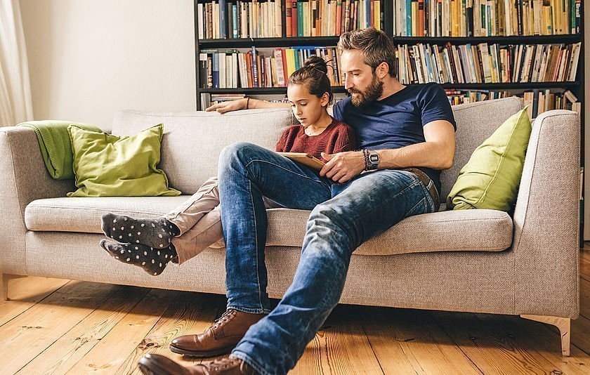 Vater und Tochter mit Tablet auf Sofa