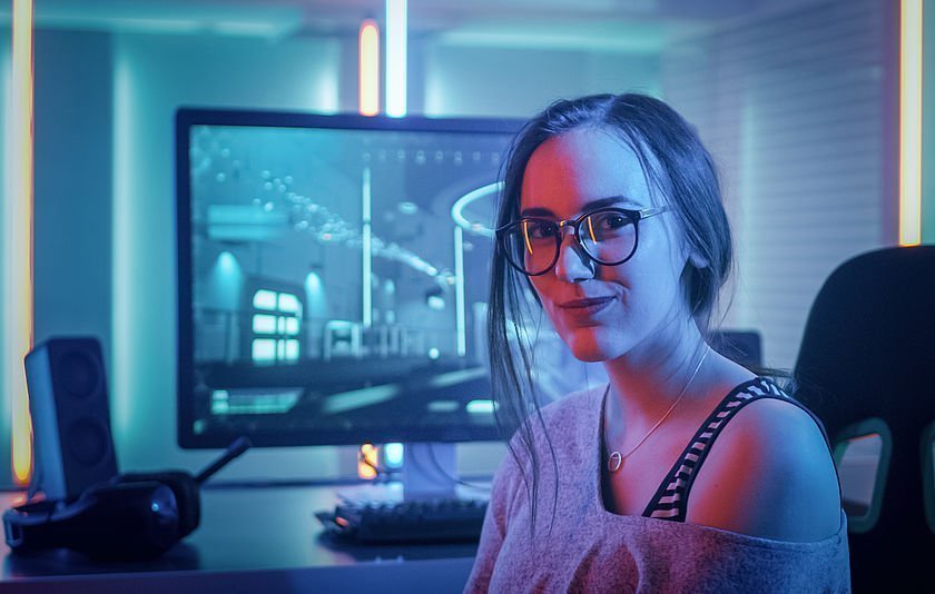Junge Frau mit Gaming-PC im Hintergrund