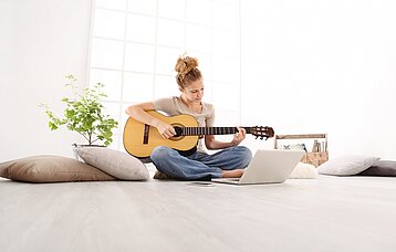 Junge Frau beim Gitarre spielen
