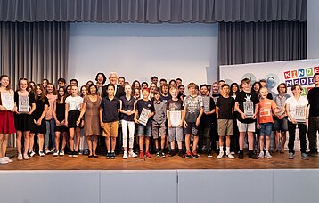Schülergruppen mit Urkunden und Ministerpräsident Winfried Kretschmann auf der Bühne
