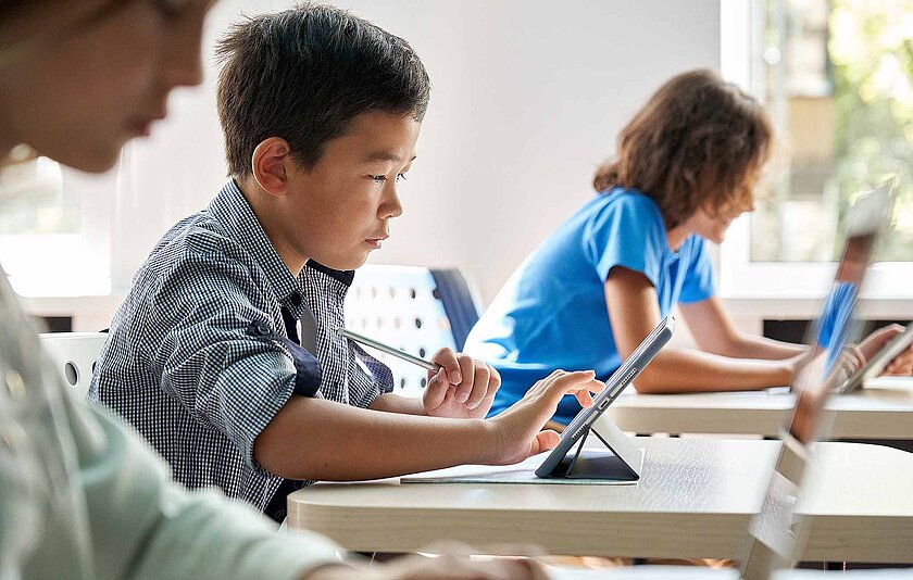 Kinder konzentriert am Tablet im Klassenzimmer.