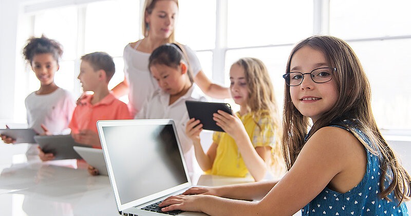 Kinder mit Tablet und Laptop im Klassenzimmer