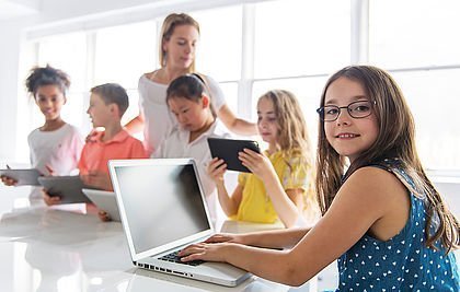 Kinder mit Tablet und Laptop im Klassenzimmer