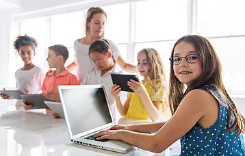 Kinder mit Tablet und Laptop im Klassenzimmer