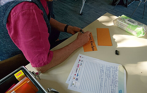 Gesundheitsbotschafter schreibt Idee auf einen Zettel Gesundheitsbotschafter schreibt Idee auf einen Zettel