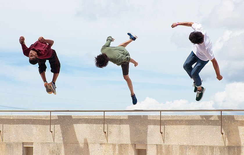 Drei Jungs springen über eine Mauer