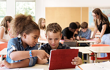 Zwei Kinder mit Tablet im Klassenzimmer