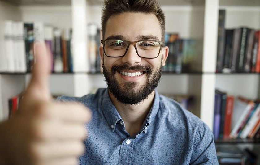 Junger Mann streckt an einer Hand den Daumen hoch.