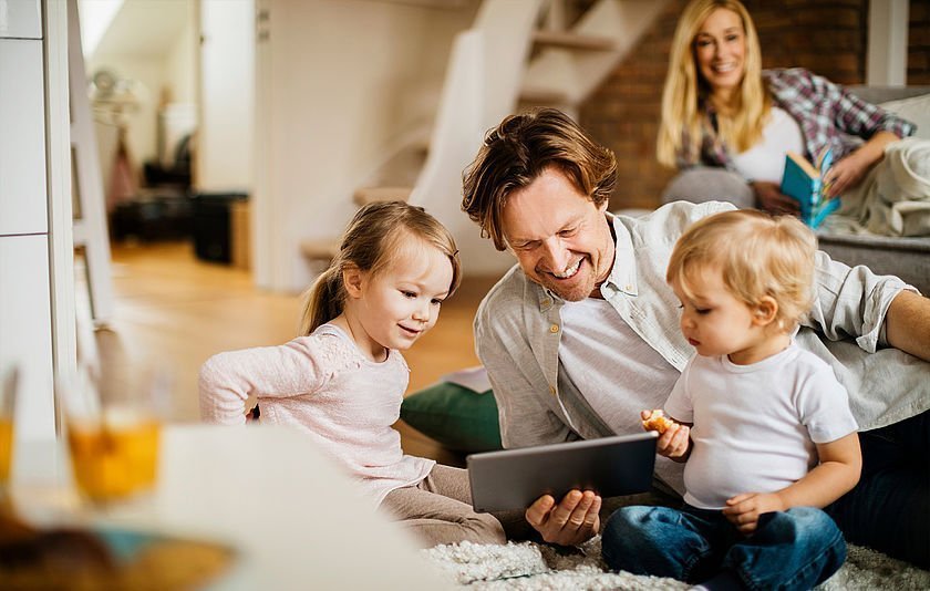 Mann mit zwei Kleinkindern vor einem Tablet