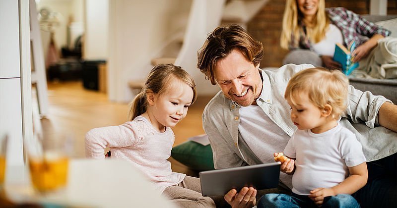 Mann mit zwei Kleinkindern vor einem Tablet