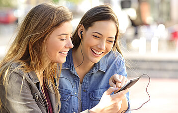 Zwei Mädchen sehen auf ein Smartphone