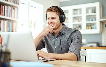 Lehrer am Laptop mit Kopfhörer