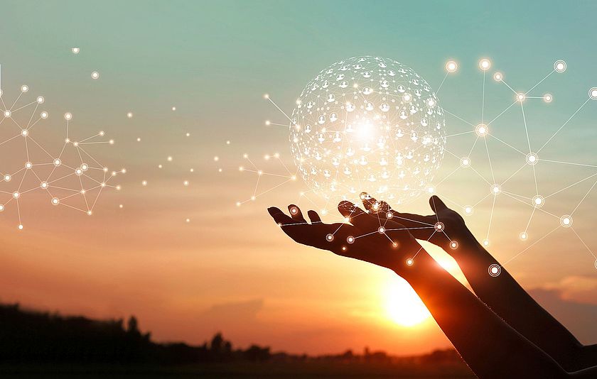 Hände halten einen aus digitalen Icons geformten Ball 