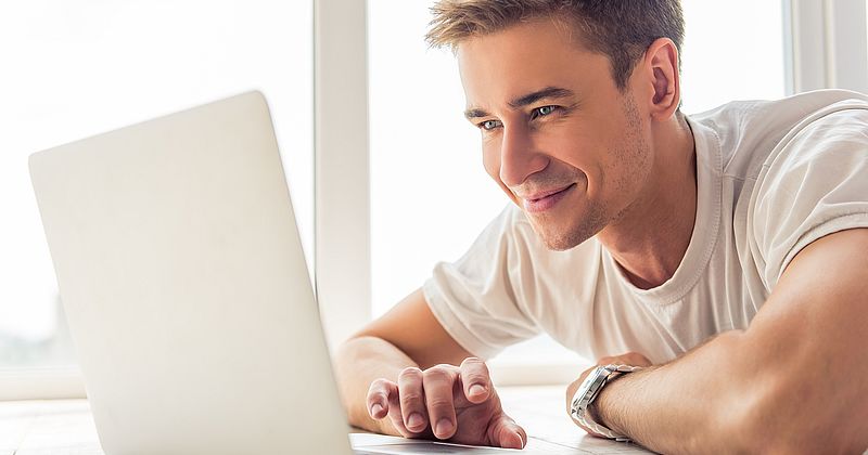 Lächelnder Mann vor einem Laptop