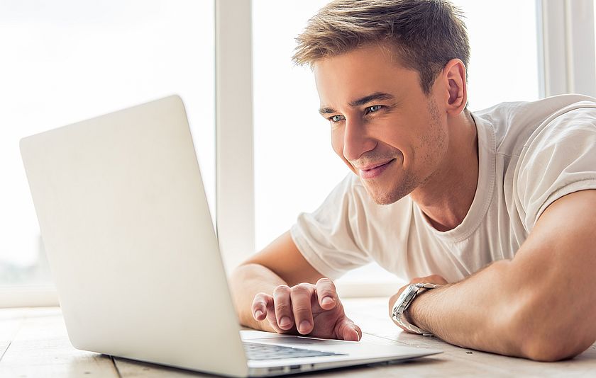 Lächelnder Mann vor einem Laptop