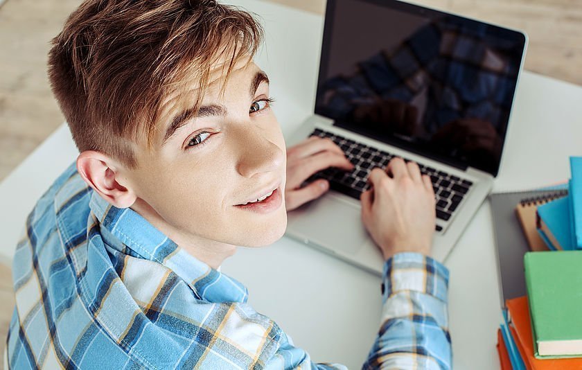 Junge sitzt am Laptop und schreibt