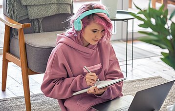 Schülerin mit Kopfhörer und Laptop in einer Videositzung