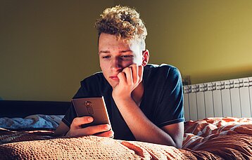 Jugendlicher schaut in sein Smartphone