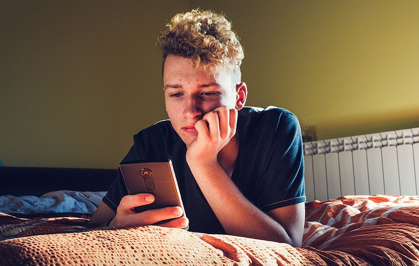 Jugendlicher schaut in sein Smartphone Jugendlicher schaut in sein Smartphone