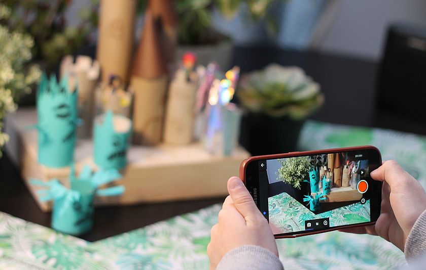 Handy fotografiert eine gebastelte Burg im Hintergrund