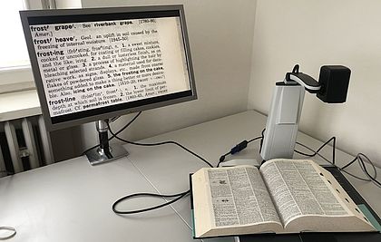 Mithilfe eines Bildschirmlesegeräts wird ein Buch auf einen PC-Bildschirm vergrößert.