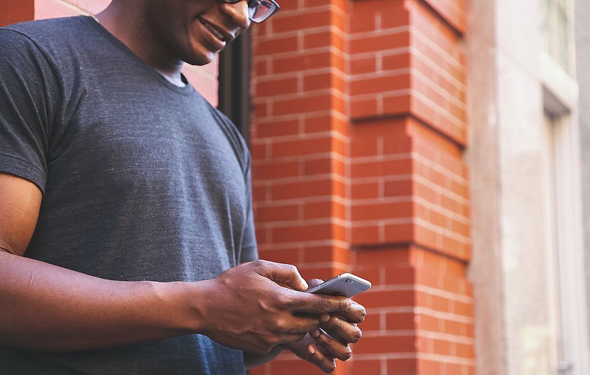 Mann mit Smartphone an Hauswand