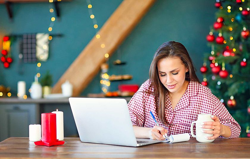 Junge Frau am Laptop vor dem Weihnachtsbaum