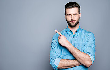 Mann zeigt mit dem ausgestreckten Finger nach oben