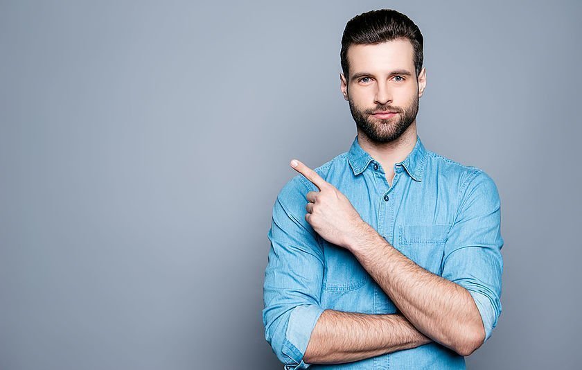 Mann zeigt mit dem ausgestreckten Finger nach oben