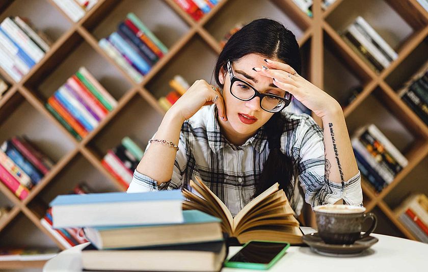 Junge Frau sitzt in einer Bibliothek