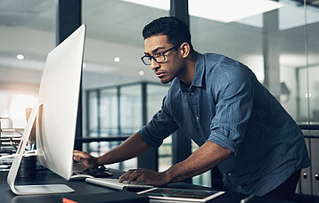 Software-Entwickler schaut in den Bildschirm-Monitor innerhab eines sehr modernen Büros.