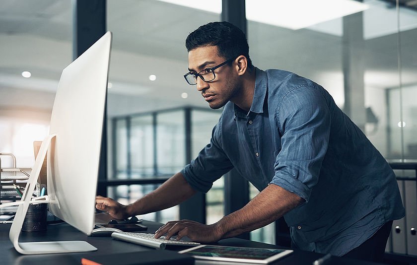 Software-Entwickler schaut in den Bildschirm-Monitor innerhab eines sehr modernen Büros.