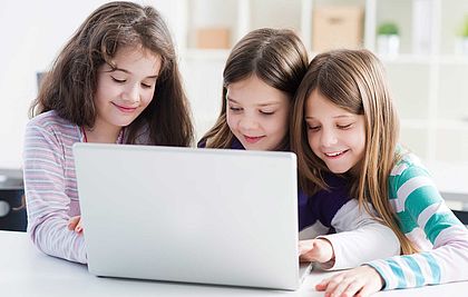 Drei Mädchen sitzen vor einem Laptop